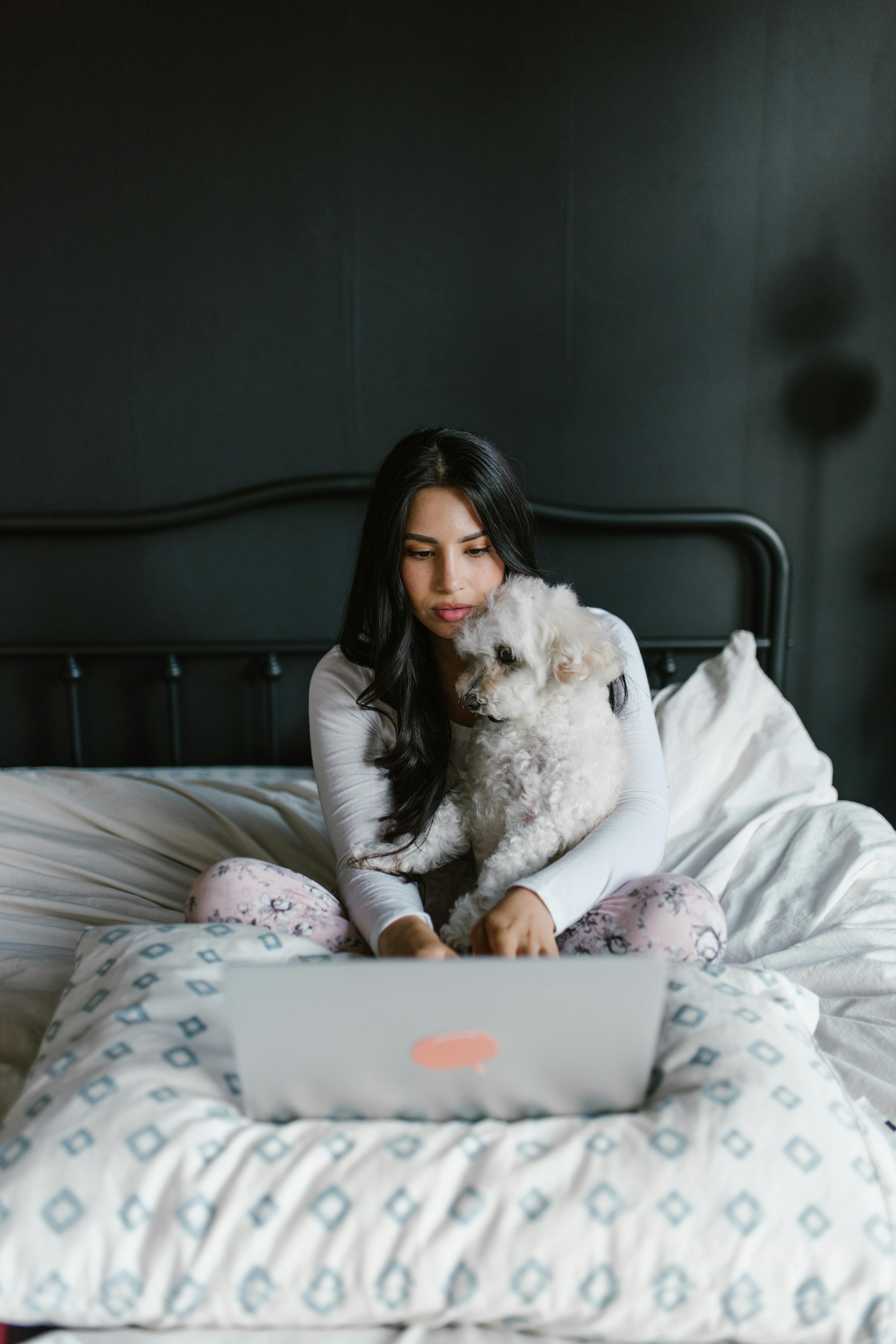 a woman sitting in her bed eviewing pet insurance documents with a dog looking with her
